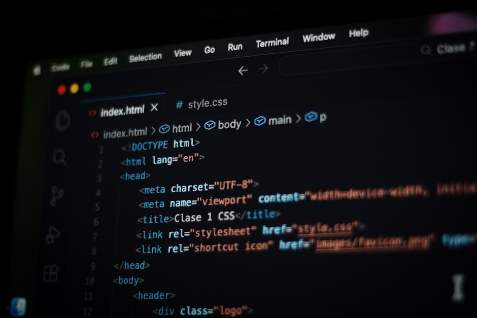 A close-up photograph of a computer screen displaying lines of HTML code in various colors, including yellow, red, white, and blue, on a dark background. The code includes tags for headings, images wi